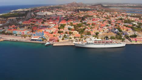 Aerial-view-of-Otrobanda-neighbourhood-with-a-cruise-ship-docked-in-St-Anna-Bay-Willemstad,-Curacao