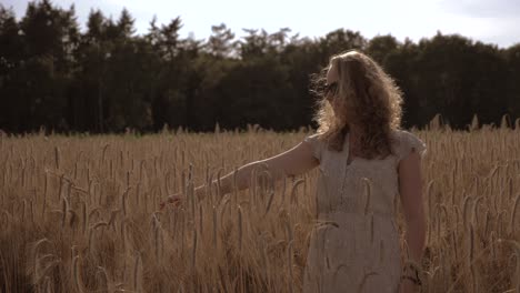 Young-woman-in-a-wheat-field,-looking-around,-on-a-sunny-evening