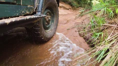 Right-outside-tire-view,-4x4-vehicle-offroad-pass-through-muddy-water