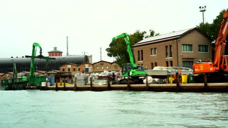 Industrial-dock,-warehouses-and-excavators-shot-from-a-boat,-on-the-canals-of-Venice