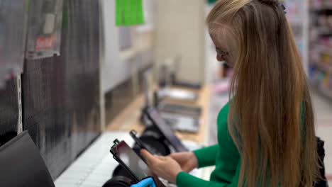Closeup-of-a-pretty-blonde-woman-looking-at-different-computer-tablets-in-a-store-display