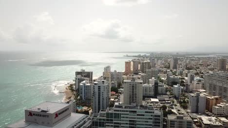 San-Juan,-Puerto-Rico,-Aerial-View-of-Waterfront,-Sandy-Beach,-Hotels-and-Buildings-Under-Beautiful-Sky