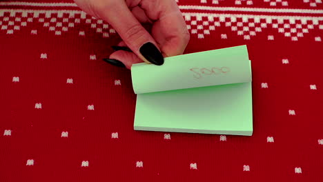 Hand-flipping-through-Post-It-notes-with-change-of-year-against-red-design-background