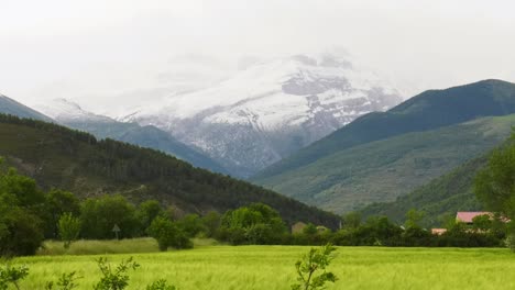 Snow-capped-Pyrenees-mountains-above-green-fertile-valley,-panning-shot