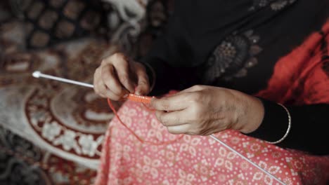 Footage-from-above-of-woman-siting-and-knitting-with-red-wool-and-needle-crafts