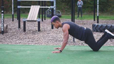 dolly-shot-going-around-a-muscular-guy-who-does-knee-push-ups-in-an-outdoor-callisthenics-sports-park