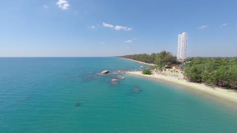 Aerial,-seascape-view-of-the-coastline-in-Rayong-called-Mae-Ramphueng-beach-with-a-tall-white-hotel-in-the-distance,-Thailand