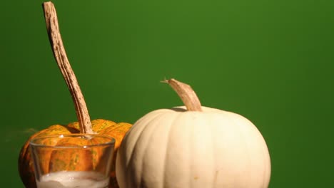 Candle-flame-blows-out-in-front-of-two-pumpkins-with-green-screen-background