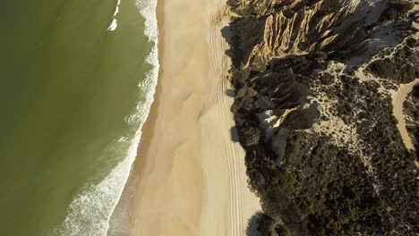 Beautiful-Scenery-Of-Lush-Rock-Formations-And-Waves-Calmly-Splashing-On-The-Sandy-Coast-Of-Gale,-Near-Camping-Praia-Da-Gale-In-Portugal-On-A-Sunny-Day---Aerial-Drone-Shot