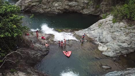 People-Enjoying-Between-Cascades-of-Charco-El-Ataud-Waterfall,-Puerto-Rico,-Aerial-View-of-Creek-Water-Falling-in-Natural-Pools