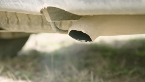 Dirty-tailpipe-coughs-exhaust-as-vehicle-starts,-close-up