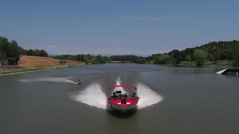 Speed-boat-pulling-water-ski-surfer-across-lake-water-fast-speeding-action