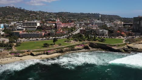 Drone-flying-in-reverse-away-from-land-over-ocean-park-in-La-Jolla-California-and-Seal-Beach