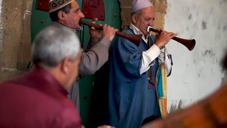 Disparó-A-Través-De-Un-Grupo-De-Hombres-Tocando-Tambores,-Primer-Plano-De-Dos-Hombres-Tocando-Rhaita-O-Mizmars-Durante-Una-Ceremonia-De-Trance-Sufi-En-Essaouira,-Marruecos