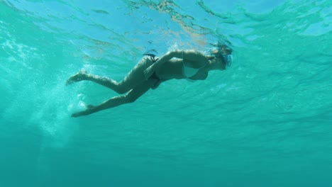 Underwater-shot-of-woman-snorkeling-in-clear-blue-sea,-view-from-below