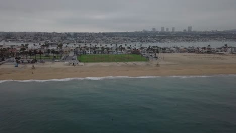 Overcast-Beach-with-Grassy-Park-and-Palm-Trees-Aerial-Pullback-over-Pacific-Ocean