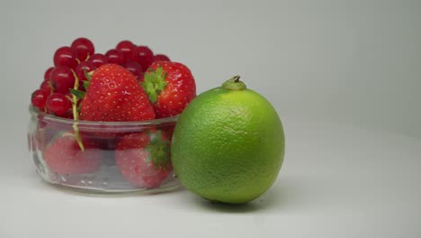 Erdbeeren-Und-Kirschen-In-Der-Weißen-Transparenten-Schüssel-Mit-Limette-Auf-Der-Außenseite,-Die-Sich-Im-Drehteller-Dreht---Nahaufnahme