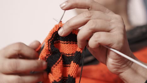 Indian-woman-knitting-a-scarf-with-red-and-black-wool-and-two-needle-crafts