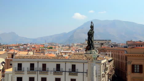 View-Of-Rooftops-In-Syracuse-And-Statue-With-Hills-In-The-Background-In-Sicily,-Italy