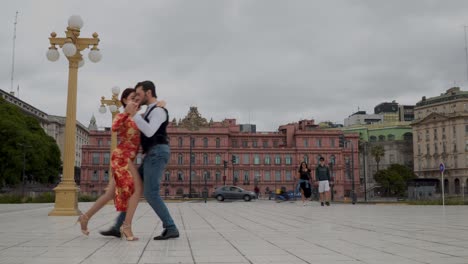 Two-professional-tango-dancers-dancing-with-Casa-Rosada-on-background