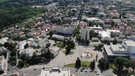 Aerial-View-of-City-in-Eastern-Europe-Featuring-Roads,-Buildings,-and-Monument-in-Town-Square