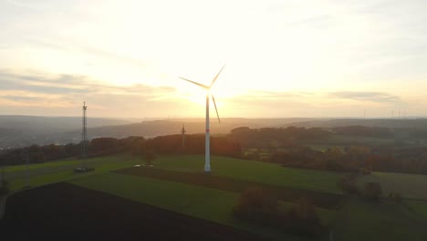 Drohnenflug-über-Grüne-Felder-Mit-Windrädern-In-Den-Sonnenaufgang