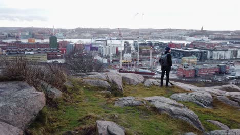 Man-standing-in-the-top-of-a-mountain-and-looking-at-Gothenburg