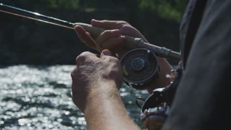 Slow-motion-footage-of-a-fly-fisherman-with-a-fish-on-his-line-and-his-reel-spooling-out-and-him-reeling-it-in