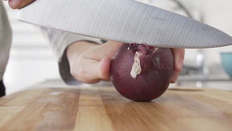 Slow-motion-as-cutting-the-ends-of-a-purple-onion-preparing-to-peel-it-in-the-kitchen