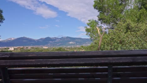 Slide-shot-of-Parnitha-mountain,-with-a-wooden-bench-in-the-foreground-60fps