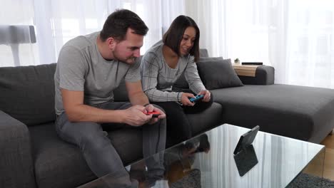 Friends-sit-on-a-couch-in-the-living-room-playing-Nintendo-Switch---Video-game