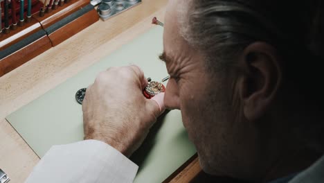 Man-Inspecting-And-Repairing-Wrist-Watch---close-up