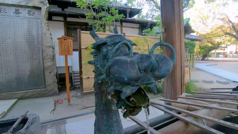 Moving-copper-dragon-spout-fountain-in-front-of-temple-in-Osaka,-Japan