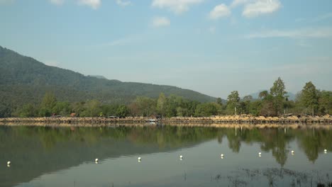 Beautiful-Huay-Tung-Tao-Lake-in-Chiang-Mai-with-a-lush-mountain-backdrop,-displaying-the-straw-huts-on-the-lake-front
