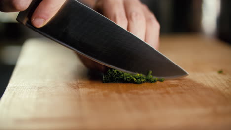male-hand-placing-chives-on-a-cutting-board,-then-starts-to-cut