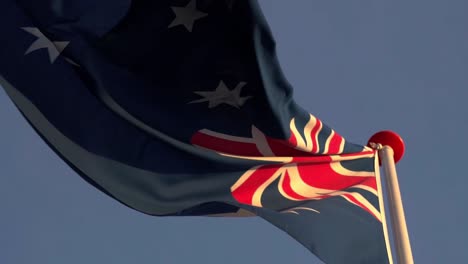 Australian-flag-waving-in-slow-motion-from-below-in-sun-against-blue-sky,-slowmotion-wind