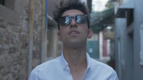 Young-man-looks-around-street-wearing-sunglasses
