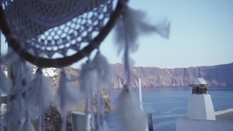 Close-up-of-a-dreamcatcher-to-a-wide-shot-of-the-beautiful-coastline-of-Santorini