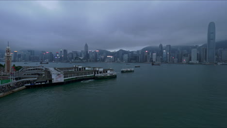 Skyline-Von-Hong-Kong-Island,-Gesehen-Von-Der-Kowloon-Waterfront-In-Der-Abenddämmerung-Unter-Stimmungsvollem-Himmel