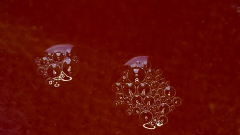 Las-Burbujas-De-Detergente-Se-Mueven-Sobre-Una-Superficie-Líquida-Roja