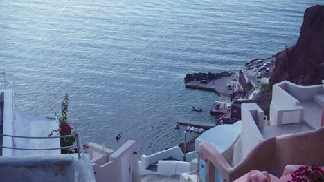 Pink-and-white-buildings-of-Santorini-from-a-high-angle-with-boats-on-a-dock-in-the-background