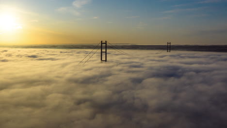 Aerial-sliding-hyper-lapse-of-fog-on-the-Humber-passing-over-the-Humber-Bridge-with-the-Sun-in-the-shot-to-begin