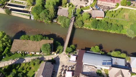 Bridge-crossing-the-Lasva-River-towards-Ribica-water-park,-Aerial-pan-up-reveal-shot
