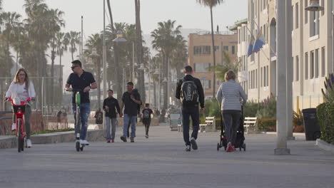 Gente-Caminando-Y-Montando-Scooters-Y-Bicicletas-A-Lo-Largo-Del-Paseo-Frente-Al-Mar-De-Santa-Mónica-En-Los-ángeles,-California