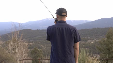 Man-talks-on-radio-while-looking-out-over-national-forest-and-wilderness-area-near-Bailey,-Colorado
