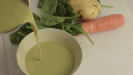 Gesunde-Gemüsesuppe-In-Eine-Schüssel-Mit-Gemüse-Im-Hintergrund-Gießen