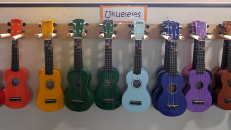 Many-Ukulele’s-Hanging-On-A-Music-Classroom-Wall,-PAN-RIGHT