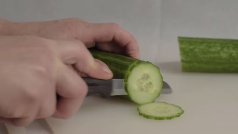 Hand-slicing-a-ripe-cucumber-with-knife-medium-shot