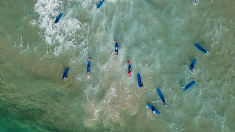 Eine-Luftaufnahme-Einer-Gruppe-Von-Menschen,-Die-Am-Strand-Surfen-Lernen