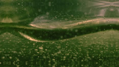 Abstract-of-green-and-golden-bubbles-slowly-floating-in-liquid-with-raindrops